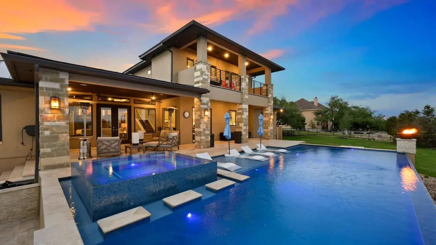 Luxury home with a landscaped pool and outdoor lounge at dusk