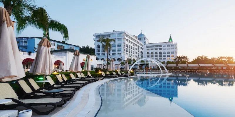 Resort pool lined with sun loungers and umbrellas at dusk