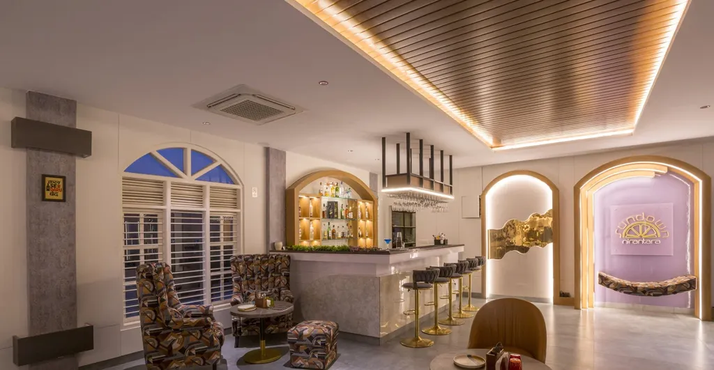 Bar counter with backlit shelves, bar stools and armchair seating under a slatted ceiling