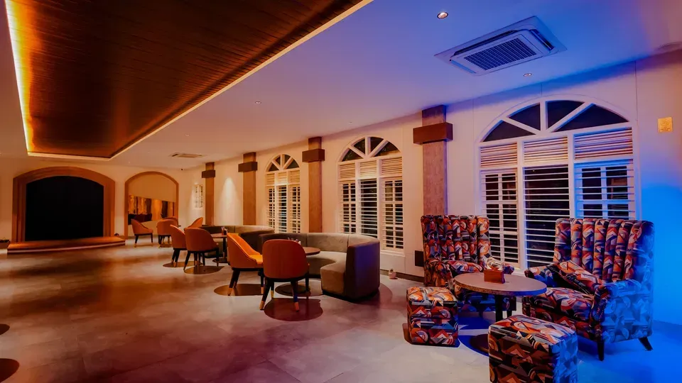 Lounge seating area with patterned armchairs, arched windows and a wood-panelled ceiling